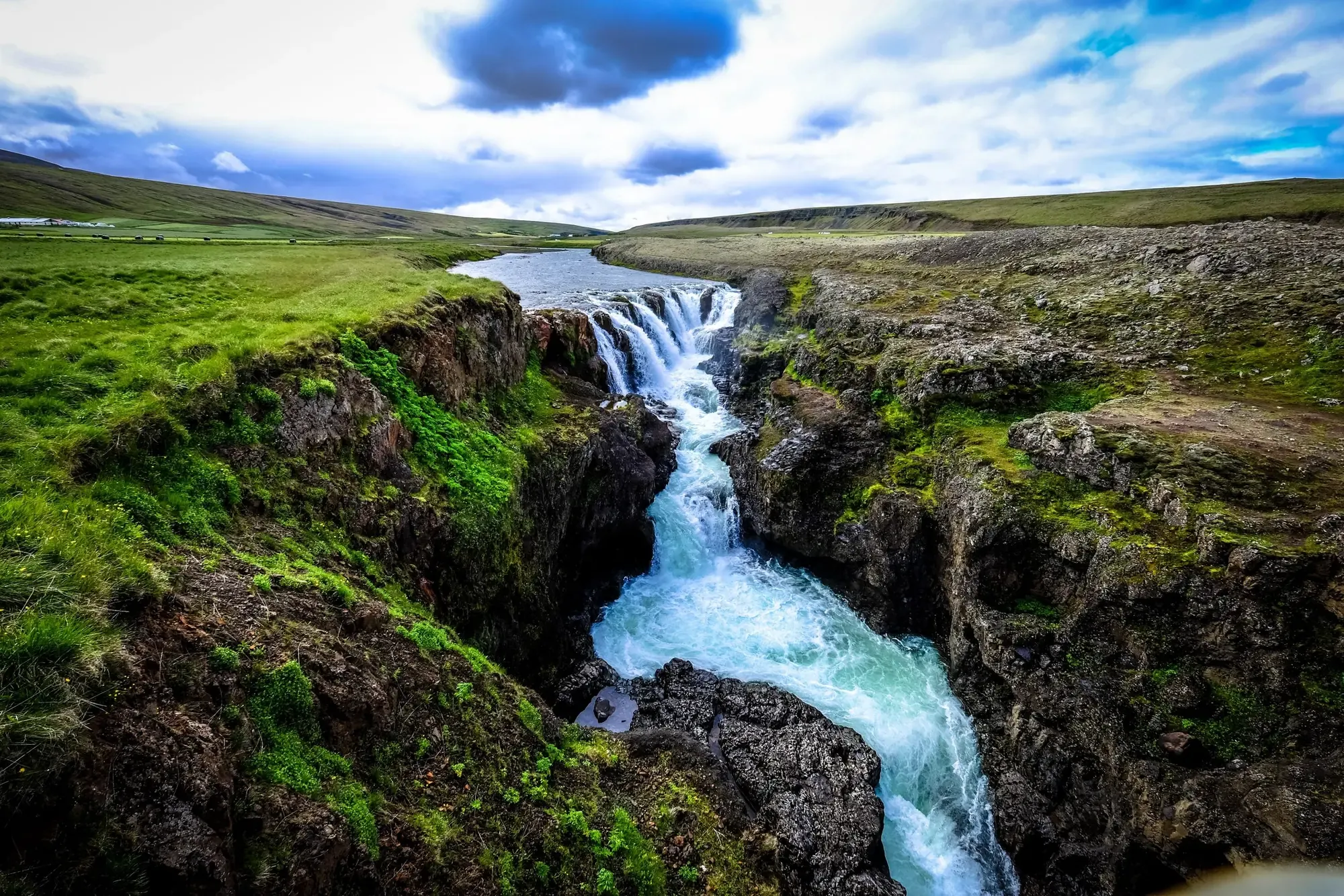 River waterfall running through a green canyon landscape