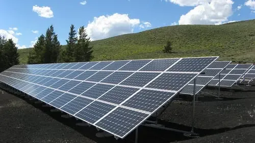 Array of solar panels in a green landscape under a blue sky